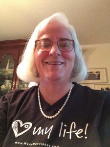 photo of Lynn Tranchell with I Love My Life shirt and pearls